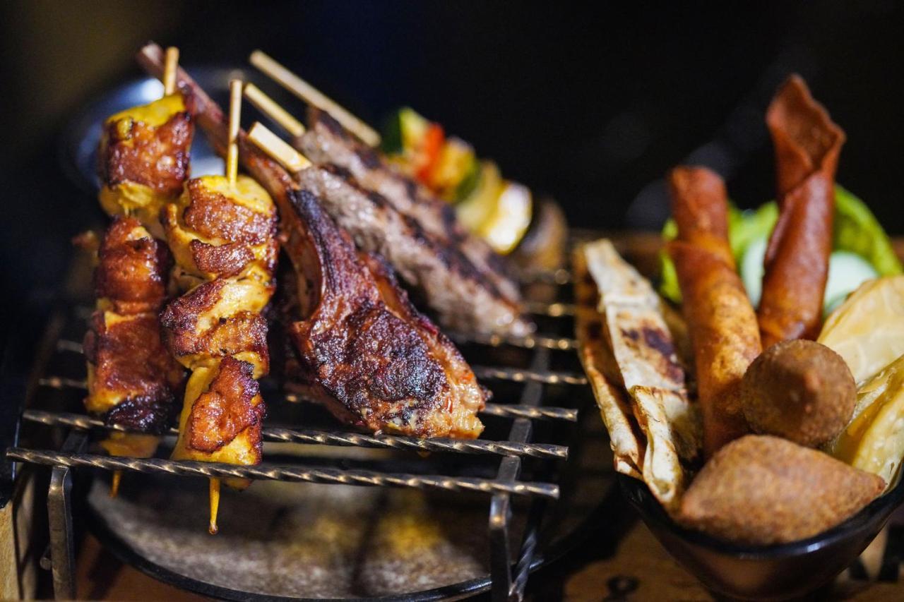 Hyatt Regency Dubai Creek Heights Hotel Exterior photo The photo depicts a variety of grilled meats arranged on a cooking grill. There are skewers with pieces of meat and vegetables, likely chicken or lamb, showcasing a mix of colors. Next to the grill, there are also several other food items, including 