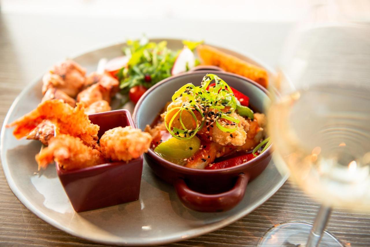 Hyatt Regency Dubai Creek Heights Hotel Exterior photo The photo presents a beautifully arranged plate of food. It features several battered and fried shrimp on the left, served in a small square dish. In the center, there's a round bowl filled with colorful mixed vegetables, likely sautéed or stir-fried