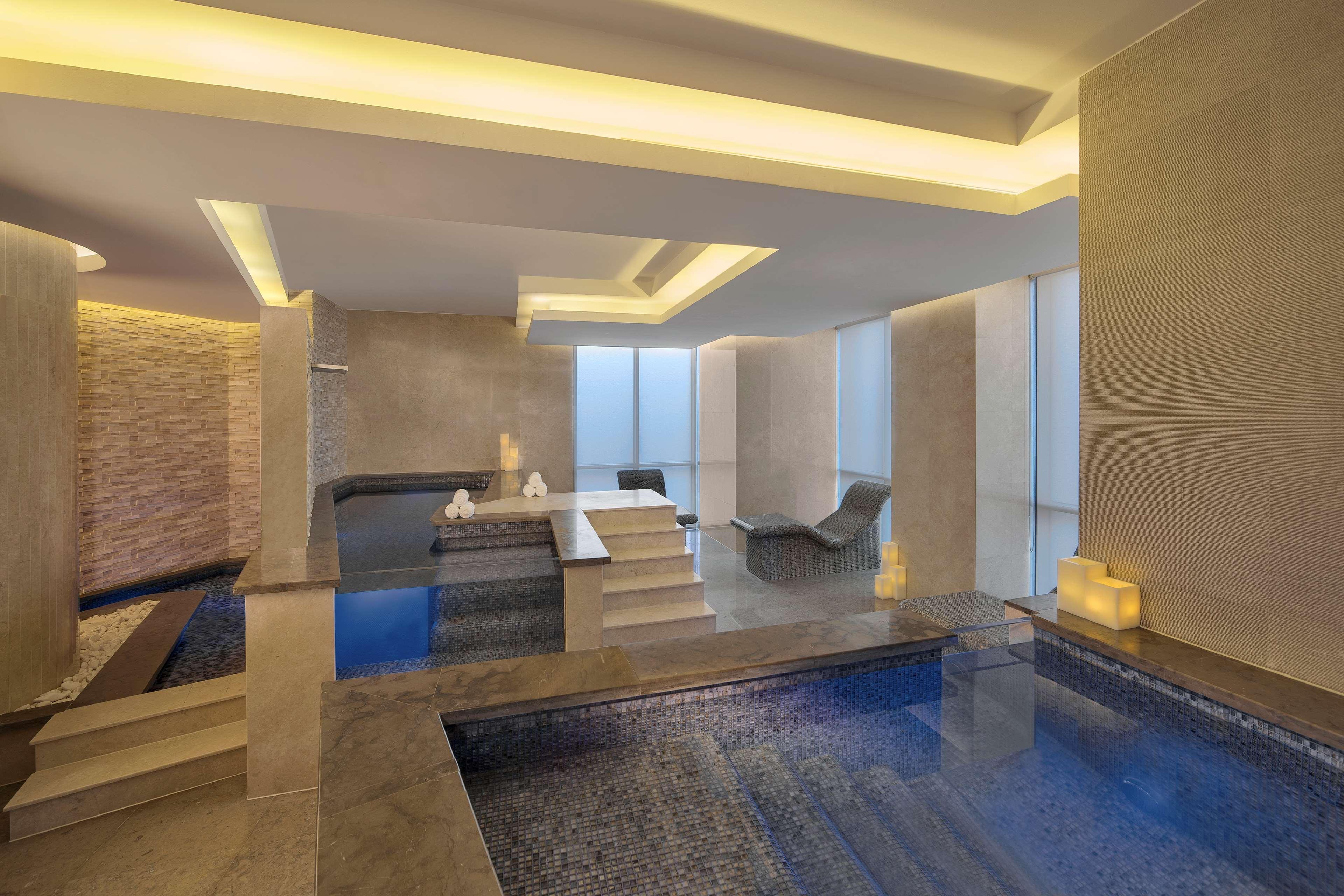 Hyatt Regency Dubai Creek Heights Hotel Exterior photo The photo depicts a modern, luxurious spa interior. It features a tranquil atmosphere with calming lighting and sleek, minimalist design elements. There are two distinct pools or water features, one of which is at a lower level, creating a multi-laye