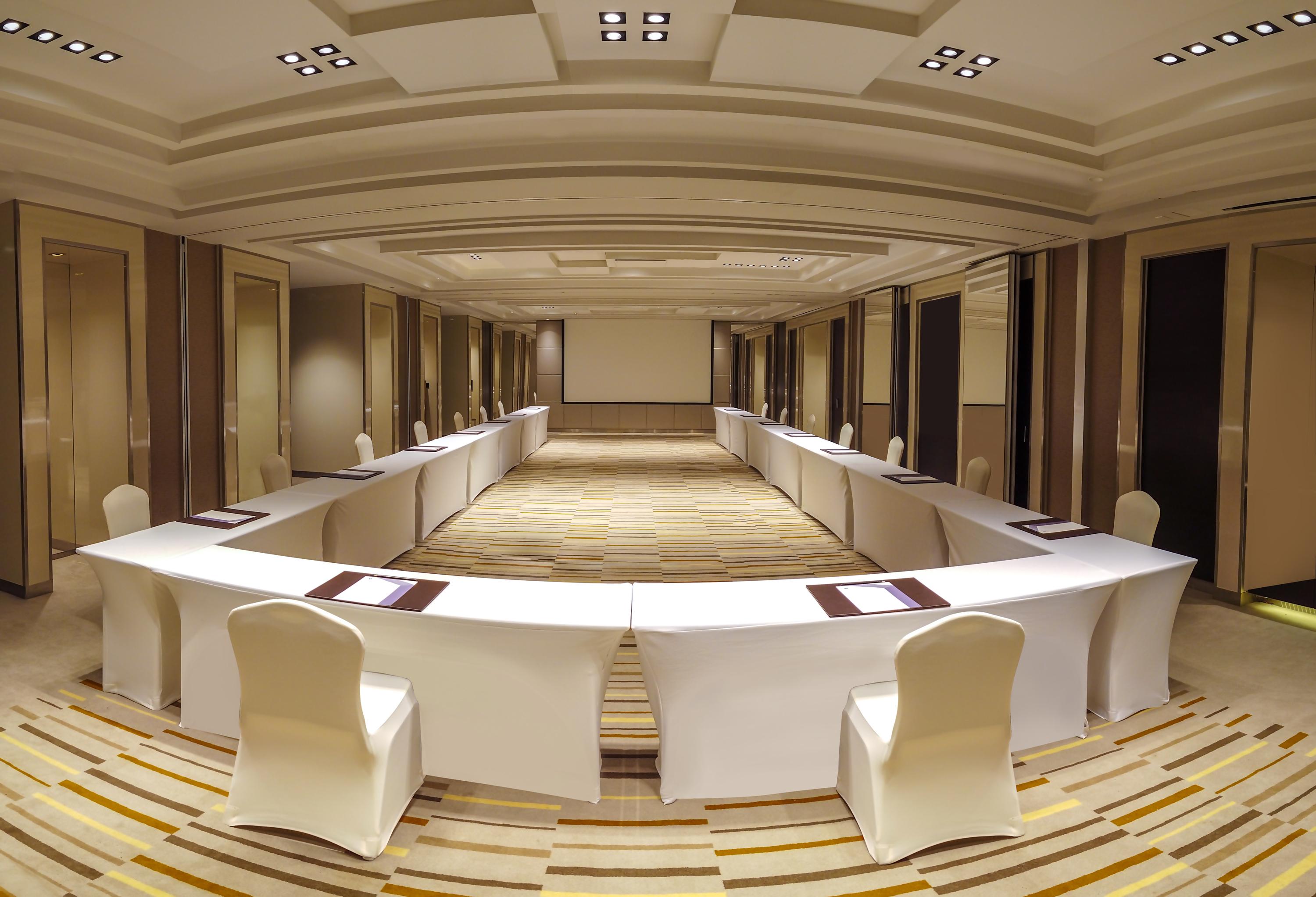 Hyatt Regency Dubai Creek Heights Hotel Exterior photo The image shows a conference or meeting room set up in a U-shape. The room features multiple white tables arranged in a way that creates a central opening, with chairs around the tables. The flooring has a striped pattern, and the walls appear to be 